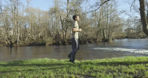 Young skinny man doing excercise wourkout by the river in the park Stock Footage 262842798