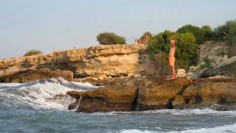 A young slender bald man in orange shorts and a naked torso stands Stock Footage 134838860