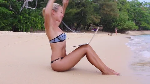 Young slender girl won  uses a laptop on the beach Stock Footage 75740227