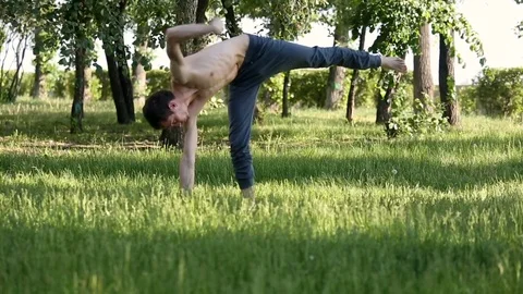 Young slender guy is meditating. Professional yoga practicing in park.  Stock Footage 77497040