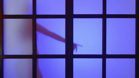 Young slim model dances behind matt glass at colorful light flashes,slow mo,4k Stock Footage 245266677