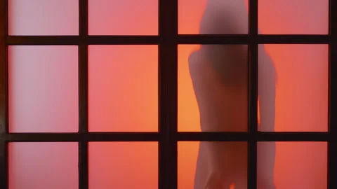 Young slim model dances behind matt glass at colorful light flashes,slow mo,4k Stock Footage 256320830