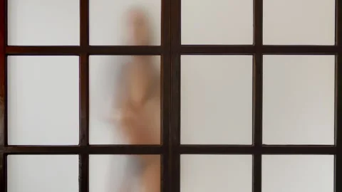 Young slim model moves slowly behind matt glass, white background, loop effect Stock Footage 304752121