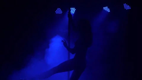 Young slim woman's silhouette dancing near the pole in dark room. Stock Footage 99046192