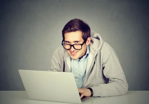 Young sly devious man using a laptop plotting server sabotage Stock Photos