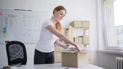 Young small online store owner packing item for delivery and marking on docum Stock Footage 112872974
