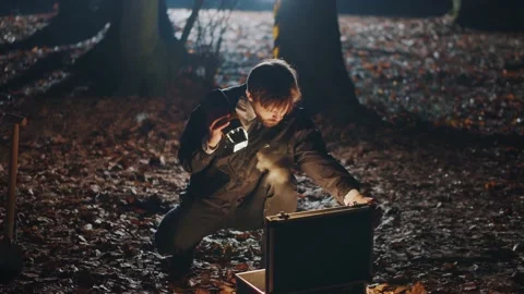 Young smart bearded man with flashlight in hand opening black briefcase in Stock Footage 201024566