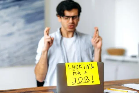 Young smart blurred hispanic man with glasses, student sits at the table, asks Stock Photos