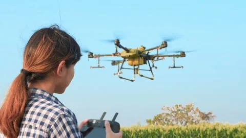 Young smart farmer controlling drone spraying fertilizer and pesticide over f Vídeos de archivo 170568750