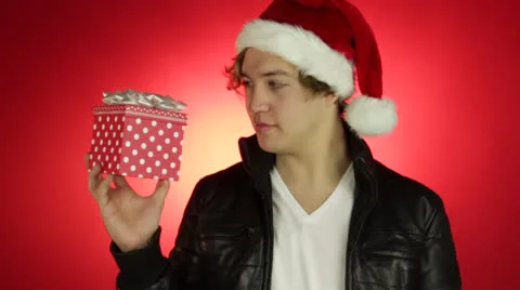 Young smart Hispanic Man holds a gift box in his hand to celebrate Christmas Day Stock Footage 22555600