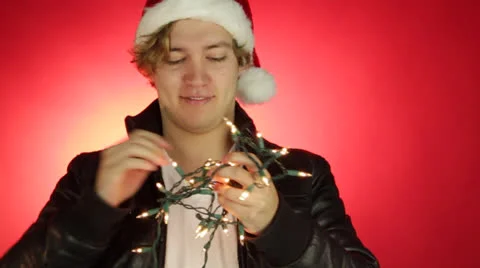 Young smart Hispanic man tries to split the knotted decorative serial lights Stock Footage 22555848