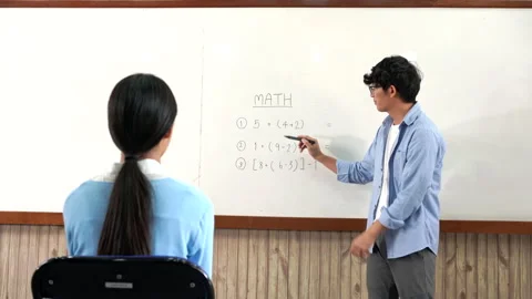 A young smart male teacher explaining decision of hard math in a classroom Stock Footage 157014460