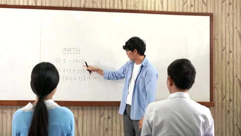 A young smart male teacher explaining decision of hard math in a classroom Video stock 157014489