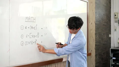 A young smart male teacher explaining decision of hard math in a classroom Stock Footage 157015625