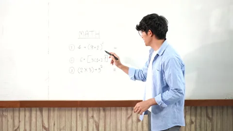 A young smart male teacher explaining decision of hard math in a classroom Stock Footage 157015996
