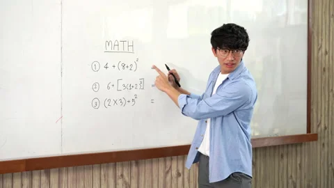 A young smart male teacher explaining decision of hard math in a classroom Stock Footage 157016026