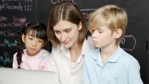 Young smart teacher using laptop to teach student programing system. Erudition. 库存照片