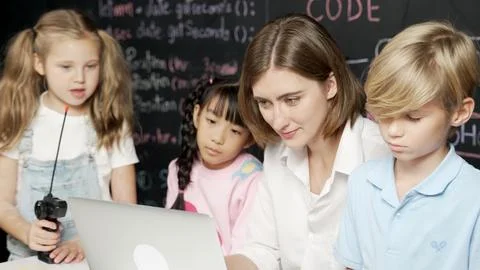 Young smart teacher using laptop to teach student programing system. Erudition. 库存照片
