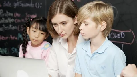 Young smart teacher using laptop to teach student programing system. Erudition. Foto stock