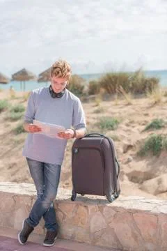 Young smiles looking at a map in a smiling way wearing a grey shirt and a blu Stock Photos