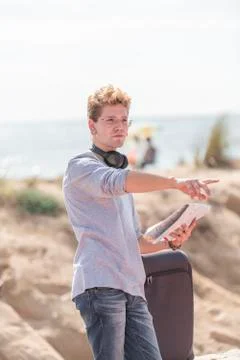 Young smiles looking at a map in a smiling way wearing a grey shirt and a blu Stock Photos