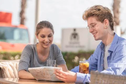Young smiles looking at a map in a smiling way wearing a grey shirt and a blu Stock Photos