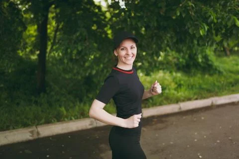 Young smiling athletic beautiful brunette girl in black uniform and cap training Stock Photos
