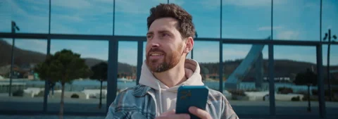Young smiling bearded man in casual clothes using smartphone, chatting on gadget Stock Footage 252139184