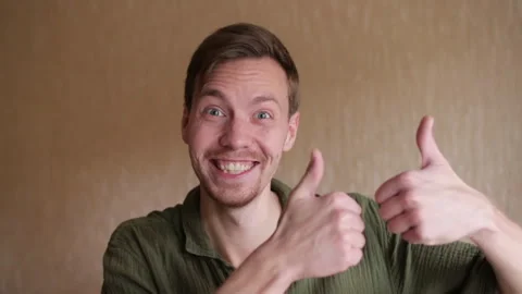 Young smiling bearded man showing thumbs up looking at camera Stock Footage 256302376