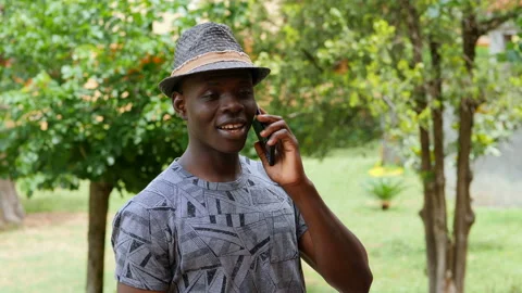 Young smiling black man talking on the phone at park on a windy day 動画素材 136509345