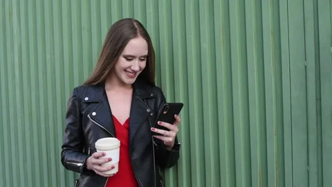 Young smiling blonde looking at her smartphone and a glass of coffee in her hand Stock Footage 141504623