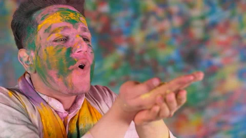 A young smiling boy blows yellow organic gulal -  color in the air, blowing c... 스톡 동영상 171113638