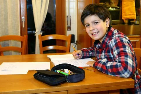 Young smiling boy does homework at his home 写真素材