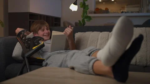 Young smiling boy with leg cast and crutches rest on comfortable sofa at ho.. Video stock 340027955
