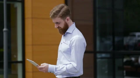 Young smiling businessman using his tablet in the street Stock Footage 64114271