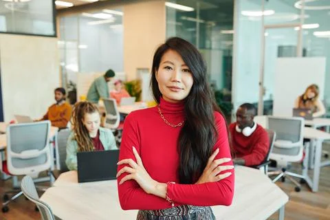 Young smiling businesswoman of Asian ethnicity crossing her arms by chest Stock Photos