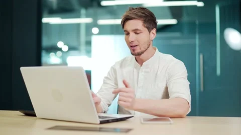 Young smiling cheerful man using video chat on laptop in office. Handsome male  Stock Footage 229086405
