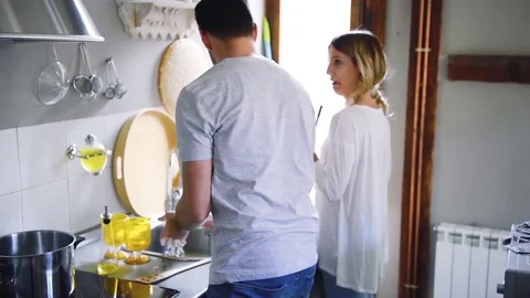 Young smiling couple playing while washing dishes in kitchen Stock Footage 74729526