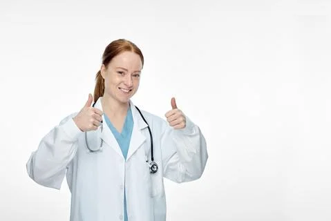 Young smiling female doctor doing thumbs up thumbs up sign Stock Photos