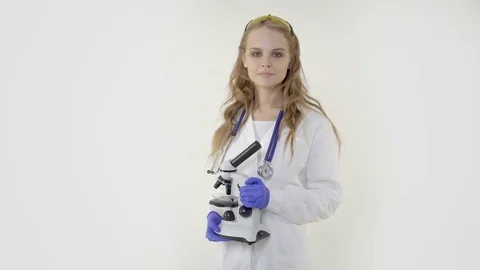 Young smiling female scientist standing with microscope over a white background Stock Footage 81691287