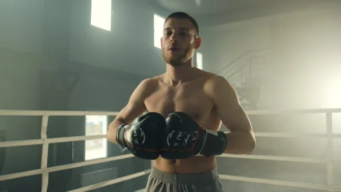 Young smiling handsome boxer doing stretching exercises before fighting Stock Footage 240582631