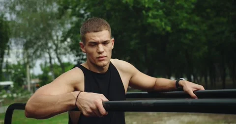 Young smiling handsome man with athletic body taking break at workout outdoors Vídeos de archivo 284128462