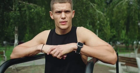 Young smiling handsome man with athletic body taking break at workout outdoors Vídeos de archivo 317966483