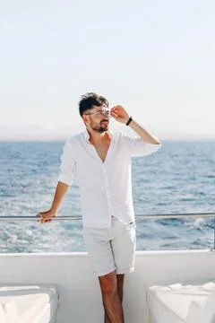 A young smiling happy man on the deck of a cruise ship looks towards the su.. Stock Photos