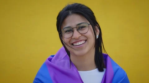 Young smiling lesbian rainbow flag on shoulders isolated yellow background. LGBT Stock Footage 240202052