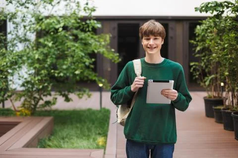 Young smiling man with backpack standing and happily looking in camera with Stock Photos