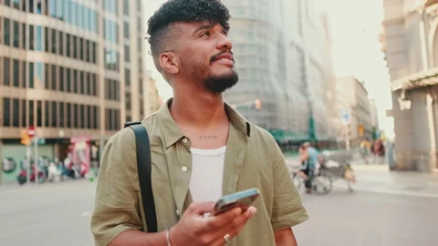 Young smiling man dressed in an olive-colored shirt stands with cellphone in his Stockbeeldmateriaal 226459835