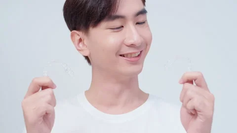 Young smiling man holding invisalign braces over white background studio, den Vídeo Stock 201669597