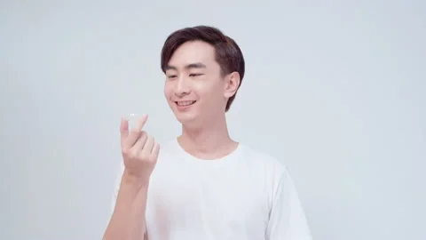 Young smiling man holding invisalign braces over white background studio, den Stock Footage 201669978