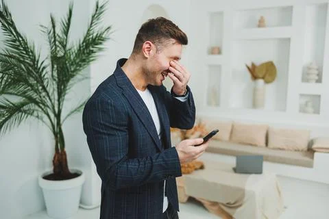 A young smiling man in a jacket is talking on the phone. Emotions of laught.. Stock-Fotos